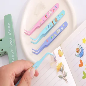 Variety of colorful cartoon tweezers used for precision sticker placement in a journal.