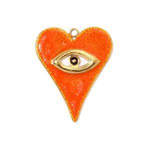 Close-up of an orange enamel heart pendant featuring a gold-toned evil eye design.