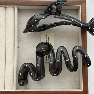 Detailed view of stylish black polka dot dolphin and wavy hair claw clips in a tray