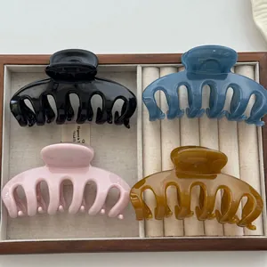 Four colorful large claw hair clips arranged in a velvet-lined display tray