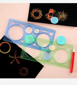Close-up of magic spirograph ruler set with gears and colorful drawings on black paper.