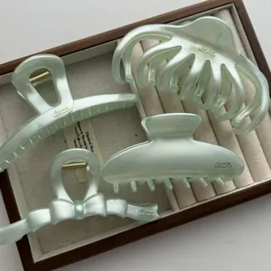 Detailweergave van vier mintgroene Franse vintage grote haarklemmen in houten tray