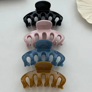 Close-up view of four colorful Korean style plastic shark hair claw clips stacked vertically