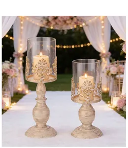 Two vintage ivory iron pillar candle holders with glass hurricanes in a wedding setting
