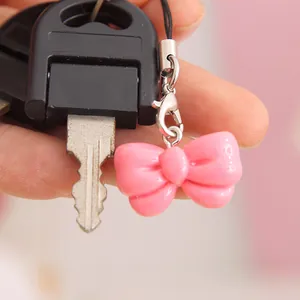 Close-up of a cute pink resin bow charm keychain accessory attached to a metal key