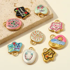 Detailed view of colorful stainless steel charms with floral and letter designs on a stone block.