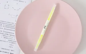 Close-up of a double-ended fluorescent yellow highlighter pen on a pink plate
