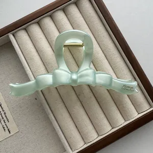 Gedetailleerd overzicht van een muntgroene haarclip in de vorm van een strik.