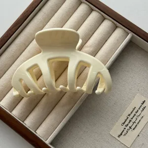 Detailed macro view of cream-colored bone-shaped hair claw clip on wooden jewelry box