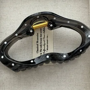 Detailed macro view of Korean style transparent black hair claw clip with white polka dots