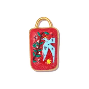Detailed close-up of a red enameled stainless steel pendant with blue bird motif