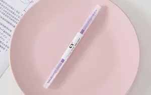 Purple double-ended highlighter on a pink ceramic plate for stationery details.