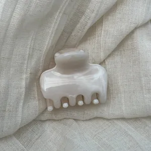 Detail of elegant marble pattern hair claw clip on soft linen fabric background.