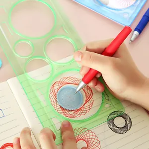 Child using a green magic spirograph ruler set to draw geometric patterns in a notebook