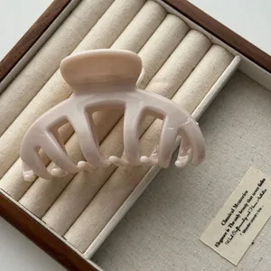 Detail of a large beige Korean style hair claw clip displayed in a wooden jewelry box.
