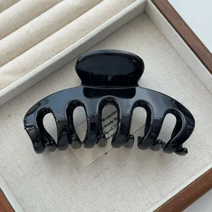 Close-up of a glossy black Korean-style shark hair claw clip in a display tray