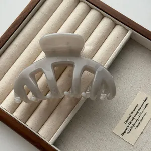 Macro detail of a minimalist light grey dragon bone hair claw clip in a wooden box