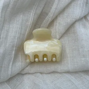 Macro detail of cream marble pattern on a French acetate hair claw clip for women's updos