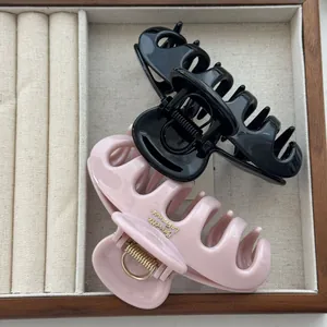 Close-up of black and pink hair claw clips with Barrette La France gold engraving.