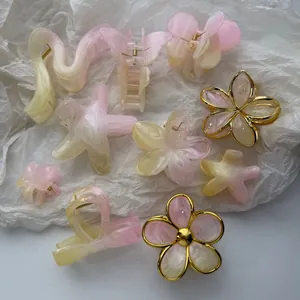 Detailed view of mixed gradient flower and starfish hair claws in pink and yellow marble