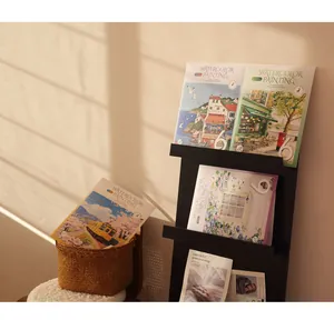 Creative watercolor painting books displayed on a shelf in warm natural sunlight