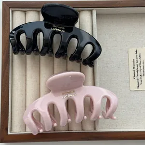 Close-up of black and pink hair claw clips with dragon bone design in a wooden tray
