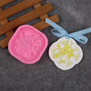 Detail of floral silicone mold and finished aromatherapy wax tablet with blue ribbon