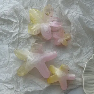 Close-up of gradient pink and yellow plumeria and starfish shaped resin hair clips.