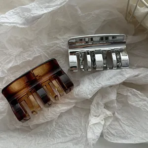 Detalle de pinzas para el cabello plateadas y de carey sobre papel de seda blanco