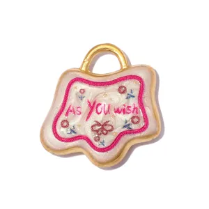 Detailed macro view of an irregular stainless steel pendant with 'As You wish' text