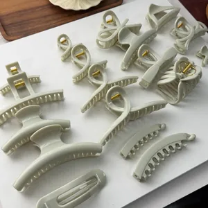 Close-up detail of various minimalist creamy green hair claw clips and large shark clips