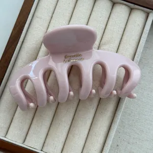 Detail showing a glossy light pink dragon bone hair claw clip in a jewelry box