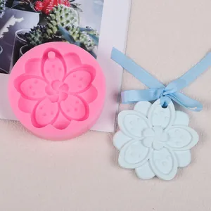 Détail du moule en silicone fleur de cerisier et pendentif en plâtre avec ruban bleu