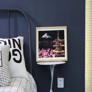 Modern square wood photo frame for scratch art displayed on a bedside table