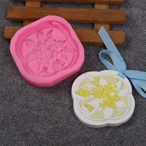 Detail of pink silicone floral mold and a finished white aromatherapy wax tablet