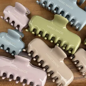 Primo piano di fermagli per capelli minimalisti in colori crema con testo HAND MADE su legno