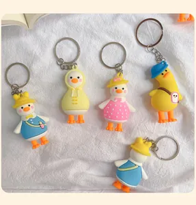 A collection of funny cartoon duck keychains in various outfits on white fabric background.