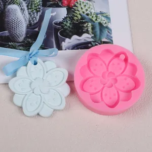 Vue rapprochée d'un moule en silicone fleur de cerisier et d'un pendentif en plâtre