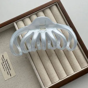 Gedetailleerd beeld van een 13cm matblauwe octopus haarklem in een luxe houten kistje.