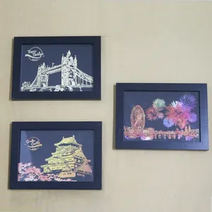 Minimalist black photo frames displaying vibrant night scene scratch art on a neutral wall