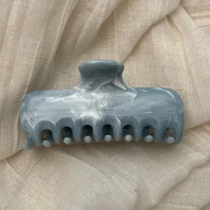 Close-up of elegant marble ink pattern blue hair claw clip on soft fabric background