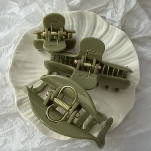 Primo piano di mollette per capelli verde oliva minimaliste di varie dimensioni su piatto