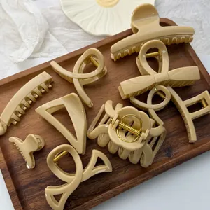 Detailed view of assorted beige hair claw clips on a wooden tray