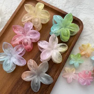 Detailopname van plumeria haarclips in gradiënt gelei kleuren op een houten dienblad