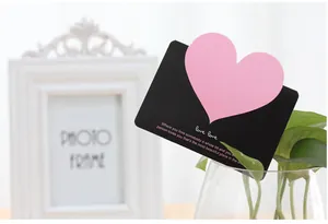 Dettaglio biglietto auguri rosa a cuore con citazione romantica su sfondo nero
