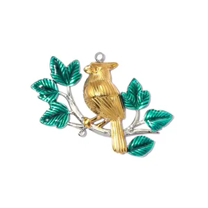 Detailed view of a golden bird pendant with green enameled leaves on a white background.
