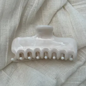 Detailed macro view of cream marble pattern hair claw clip on soft linen fabric background
