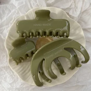 Primo piano di fermagli per capelli verde oliva fatti a mano in tre stili su un piatto