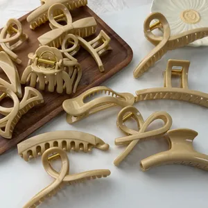 Detailed view of multiple beige minimalist hair claw clips displayed on a wooden tray