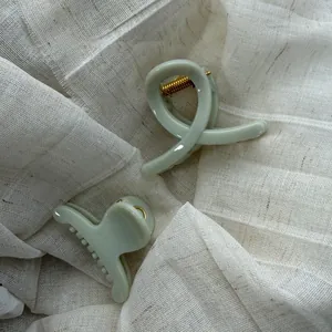 Detail view of large sage green minimalist hair claw clip on white linen.